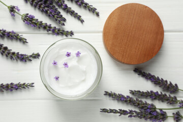 Obraz na płótnie Canvas Jar of face cream and beautiful lavender on white wooden table, flat lay