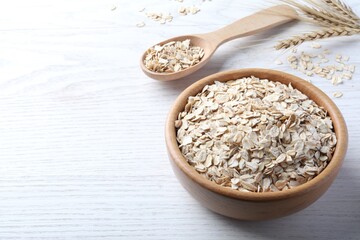 Oatmeal, bowl and spoon on white wooden table. Space for text