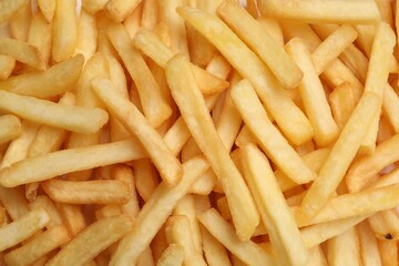 Many delicious French fry pieces as background