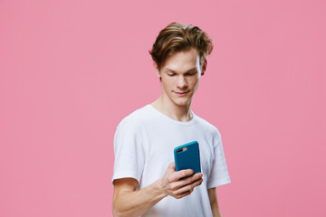 Fototapeta premium cute nice guy with a thoughtful smile typing a text message on the phone