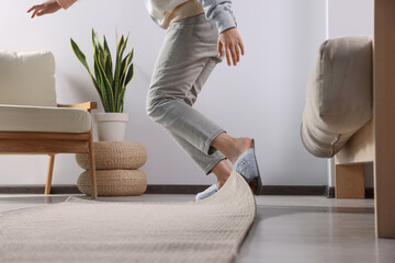 Woman tripping over carpet at home, closeup - obrazy, fototapety, plakaty