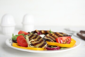 Delicious salad with roasted eggplant served on white wooden table, closeup