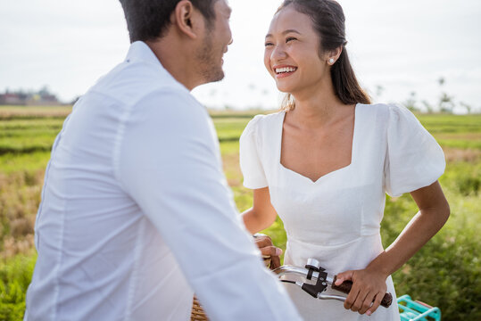 romantic couple looking at each other and laughing while riding a bike in countryside