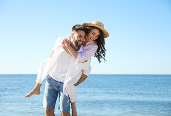 Happy young couple having fun on beach near sea. Honeymoon trip