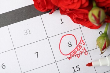 Roses and red marker on calendar near date 8th of March, above view. International Women's Day