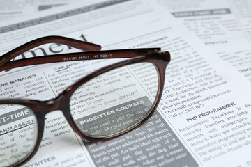 Glasses on newspaper, closeup view. Search concept