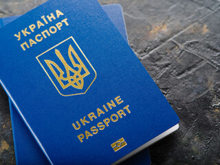 Close-up. Two blue Ukrainian biometric passports on a gray background. Travel abroad, visa...