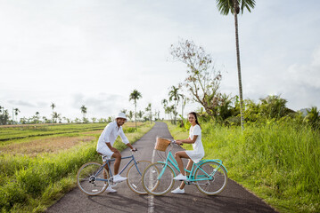 beautiful asian young couple wearing white dress enjoy riding their bicycle together