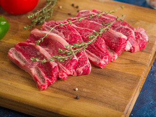 Close-up. Raw meat steaks with rosemary on a wooden cutting board. Ready for grilling. Picnic, barbecue. Family traditions. Delicious healthy food, healthy lifestyle.