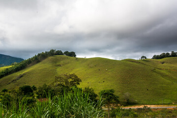 Obraz premium Landscape of a pasture in a hill in a cloudy day in the town of Macuco, State of Rio de Janeiro, Brasil.