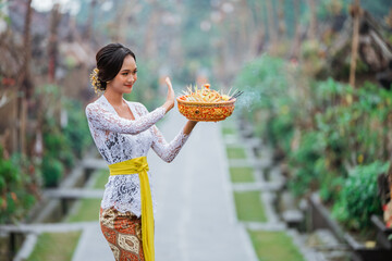 pretty balinese woman carrying an holy offering for praying to god
