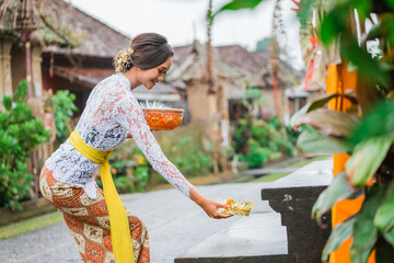 balinese woman do the prayer to god in the morning. hindu make an offering to their god using canang
