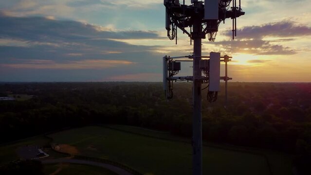 Flying around cell phone signal translation tower during early morning hours. Rising sun is passing through equipment creating pattern of blinking light.