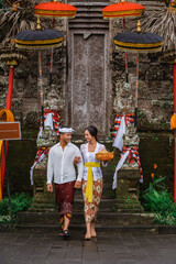 Naklejka premium couple with balinese traditional clothing walking in front of pura gate