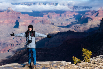 Fototapeta na wymiar Teen arms outstretched on edge of grand canyon Arizona USA