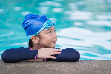little girl smiling wearing swimming glasses in swimming pool. children playing in swimming pool on summer.