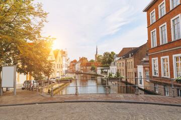 Fototapeta na wymiar Scenic city view of Bruges canal with beautiful medieval colored houses, bridge and reflections in the evening gold hour, Belgium