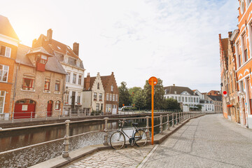Scenic city view of Bruges canal with beautiful medieval colored houses and old bike in the morning hour at sunrise, Belgium