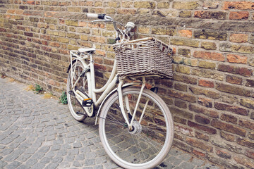 White vintage bicycle standing in front of brick wall in the city of Bruges, Belgium