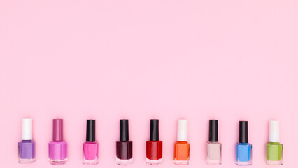 Colorful nail polish bottles on pastel pink background. Flat lay copy space