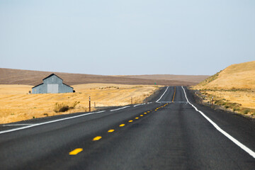 Rural highway, country road, view of old barn and golden fields  © The Adaptive