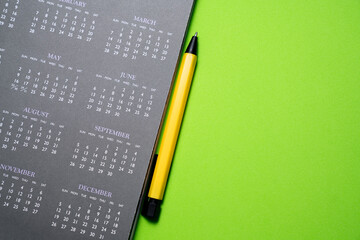 close up of calendar and pen on the green table background, planning for business meeting or travel planning concept