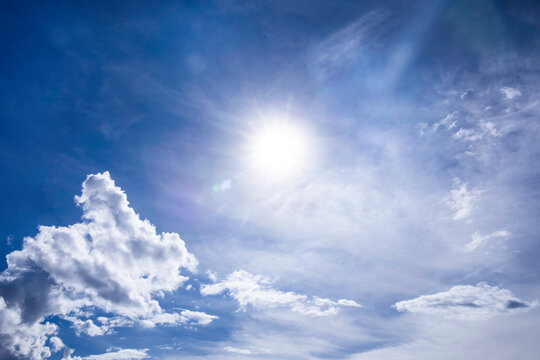 Radiant sun in a cloudy blue sky with clouds