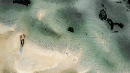 A boat is seen from above on a low tide sand beach in Samui island Thailand