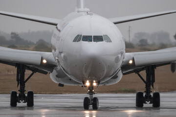 Fototapeta na wymiar acercamiento a la nariz de un avion de pasajeros rodando en la pista de aterrizaje en un dia tormentoso