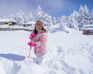 happy little girl playing outside in the snow with clear sky