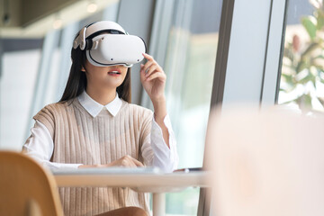 smart attractive asian female business owner weared virtual reality glasses enjoys casual metaverse...