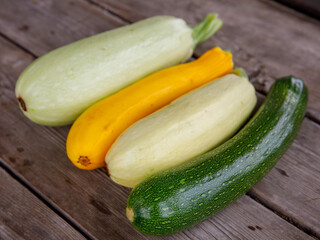 fresh mixed yellow, white, stripped and green zucchini's on a wooden background. Top view flat lay, close up