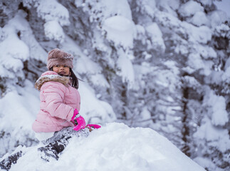 Fototapeta na wymiar happy little girl playing outside in the snow with clear sky