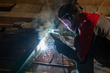 Welder in a protective suit and mask at work