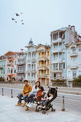 portrait of asian family sitting on a bench with beautiful building at the background
