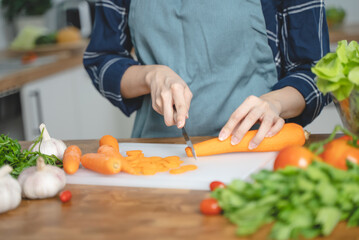 Asian housewife woman slice carrot to preparing salad ingredients for dinner meal  in the kitchen
