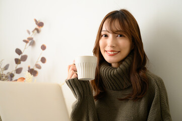 コーヒーを飲みながら仕事をする女性　秋冬