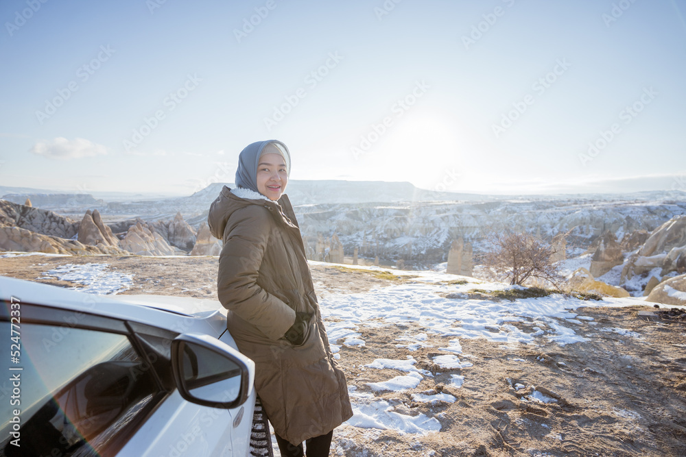 Wall mural portrait of young asian woman on her adventure going to beautiful hill in cappadocia in winter by her car