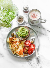 Homely cozy breakfast table - omelette, vegetables, avocado toast and cappuccino on a light marble background, top view