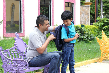 Latino dad checks his son's backpack on this return to school to check that he does not carry weapons or illegal substances
