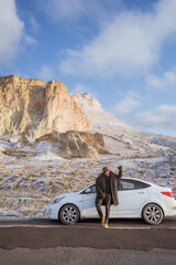 portrait of young asian man on his adventure going to beautiful hill in cappadocia in winter by his car