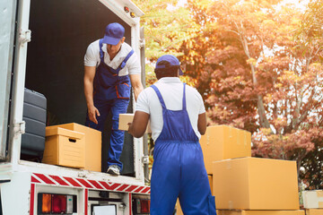 Couple courier house mover handover cardboard box in to the truck. © ztony1971