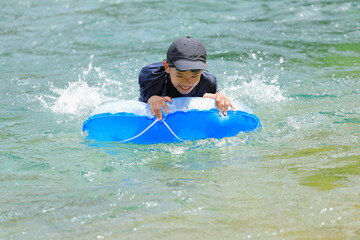 川で浮き輪で遊ぶ男子中学生 (12歳)