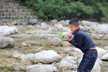 水鉄砲で川遊びをする男子中学生 (12歳)