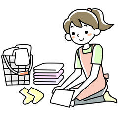 エプロンを着けて洗濯物をたたむ若い女性