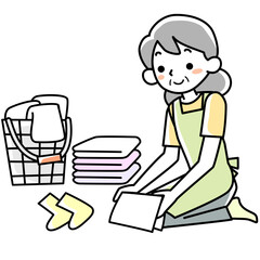 エプロンを着けて洗濯物をたたむシニア女性