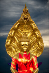 A peaceful superimposed and double exposure images of Golden Buddha statue and a pink lotus with a cloudy sky in the background.