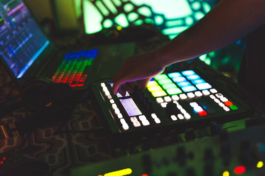 DJ playing electronic music with modern MIDI controller, green stage lighting