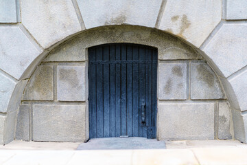 Wooden door of black color in a stone arch