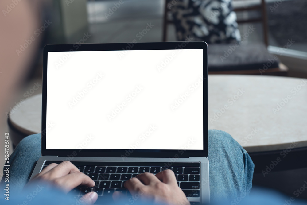 Sticker Mockup image of laptop computer. Casual business man, freelancer using and typing on laptop computer with blank white screen at coffee cup, over shoulder view